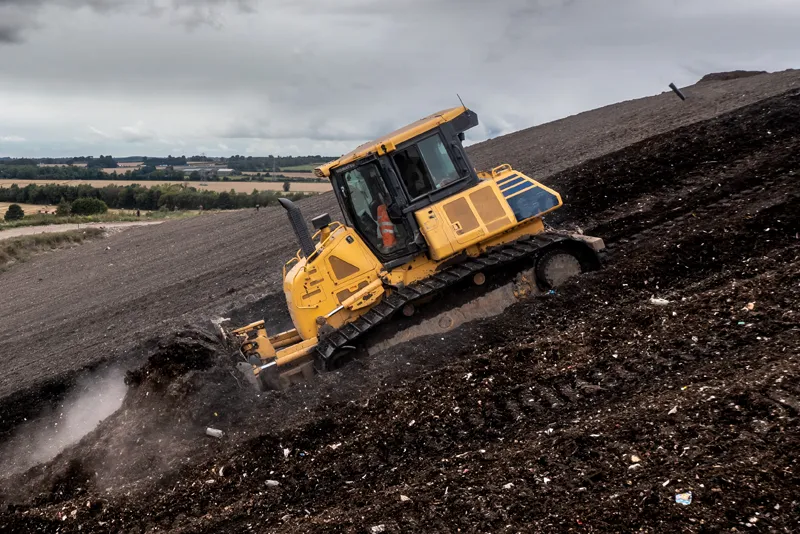 Construction worker on slope of landfill